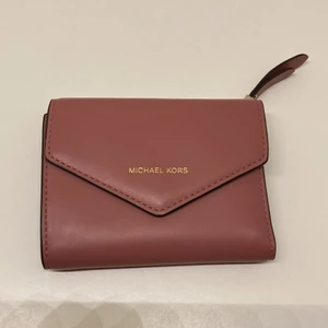 Michael Kors Pink Wallet  - Brand : Micheal Kors, Färg : Rosa, Material : Läder. Storlek : H : 9cm x L : 11,5cm  Bra condition men det finns en liten fläck på baksidan. 