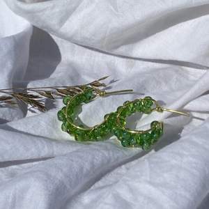 Handgjorda örhängen med gröna pärlor, och guldpläterad koppartråd. Nickel-, kadium-, och blyfria. OBS! Kommer utan plupp att sätta på baksidan.  2,5 cm i diameter