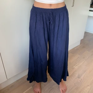 Pösiga byxor  - Mörkblåa pösiga byxor med resorband. Slitsar upp till käna på båda benen!