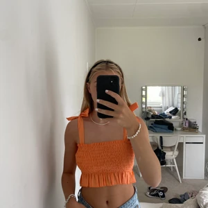 Orange topp med knytband  - Orange topp i smock med knytband. Storlek S men stretchig så passar även xs och M. Aldrig använd, endast provad. 