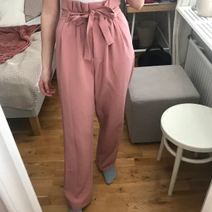 Kostymbyxor från Bikbok - Super fina högmidjade och våriga kostymbyxor från Bikbok i storlek S. Jätte skönt material med skärp i midjan, så du kan välja själv hur hårt du vill knyta. Jag är 1,69 och de går hela vägen ner och nuddar marken lite utan skor. Bra skick💓🌷💕