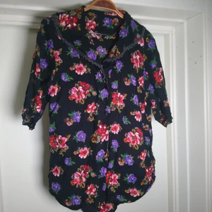 Vintageblus - Superfin vintageblus i svart med blommor. Krage med spetskant. Ingen storleksmärkning men är M/L🌹
