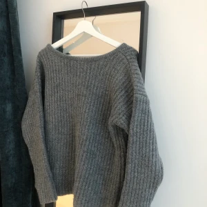 Stor stickad tröja - Stor grovstickad tröja från NAKD. Mörkgrå färg och med en V ringning i ryggen. 