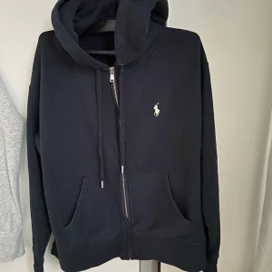 Ralph Lauren zip hood xs-s  - Ralph Lauren marin blå huvtröja med dragkedja inköpt på Pondus home of brands i Karlstad djurfritt hem tvättad i neutral tvättmedel nån enstaka gång. Lite oversize storlek xs-s fint skick 