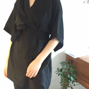 Svart kimono - Fin helt oanvänd svart kimono i faux sidentyg. Kan användas både som topp och som klänning. Säljer den då den inte används. Köpare betalar frakt. Kan även mötas upp i Malmö.