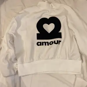 En vit polo tröja med texten amour på💞 tröjan är från H&M och har nypriset 250kr köparen tår för frakten!