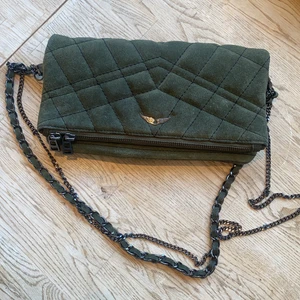 Zadig & Voltaire väska - Zadig & voltaire axelremsväska i mocka och mossgrön färg. Ett par år gammal men väldigt sparsamt använd. Klassisk modell med magnetknappar och fack med dragkedja. Två kedjor som fina detaljer. Får plats med allt nödvändigt. Nypris 3500, högst pris vinner