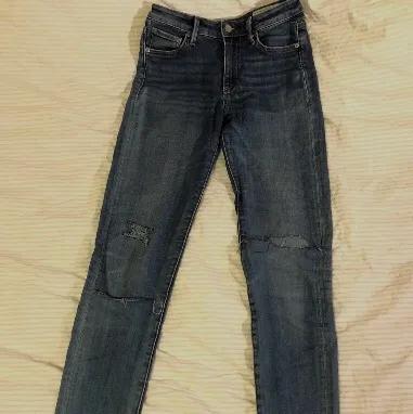 Blåa, hudnära jeans med slitningar i stretchigt tyg från Crocker. Storlek 26/32. Två fram- och bakfickor samt myntficka. Egengjorda slitningar. Väl använda så lite tunna i tyget, men mycket bekväma.. Jeans & Byxor.