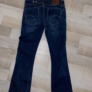 låg midjade,bootcut Jeans, G-star raw - Skit snygga lågmidjade bootcut jeans från G-Star. Tyvärr tycker jag att de sitter lite för lågt på mig och aldrig haft de ute, bara testat hemma. Haft en tidigare ägare därför väldigt billiga! Ursprungspris: 1499kr, men de jag säljer är i god skick,inga hål/märken eller något besvärligt som helt nya!