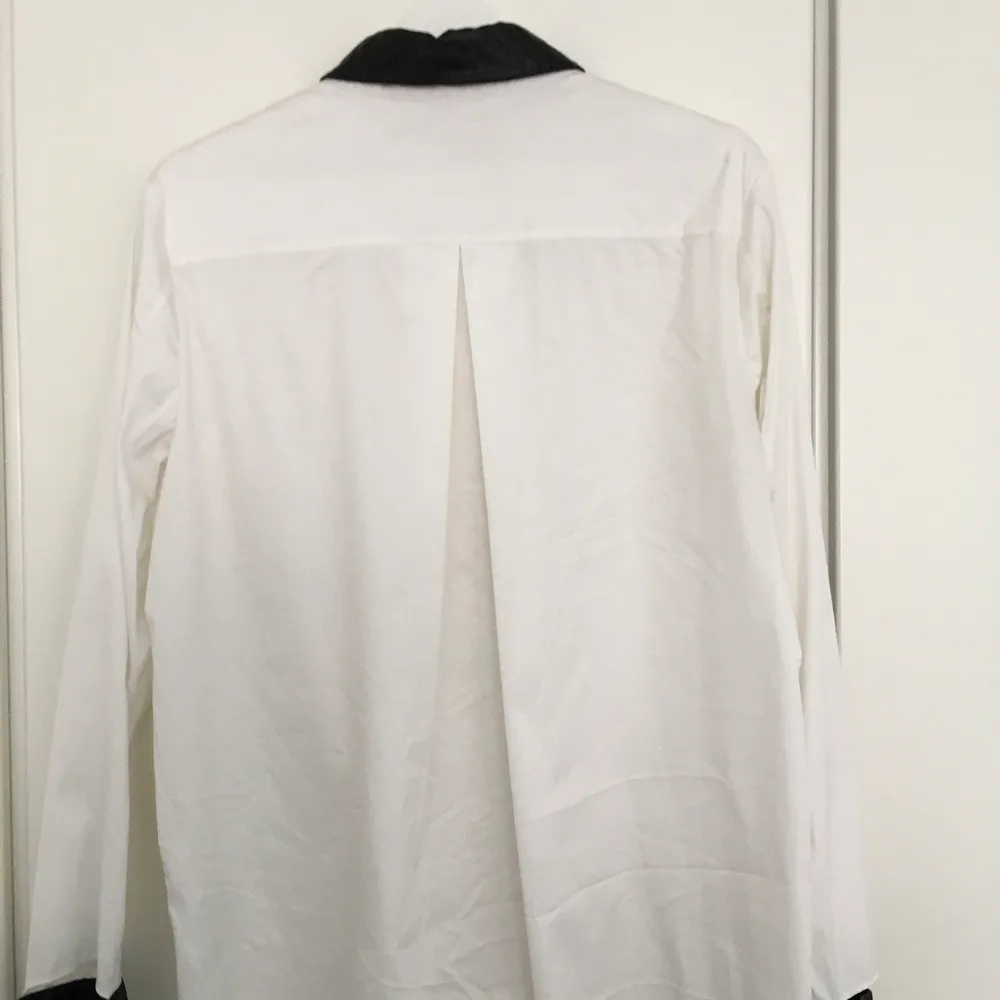 Vit bomullsskjorta med svarta lammskinnsdetaljer kring kragen och ärmar. Använd fåtal gånger, i mycket gott skick. Storlek EU 38  Nypris: 2300 SEK. Skjortor.