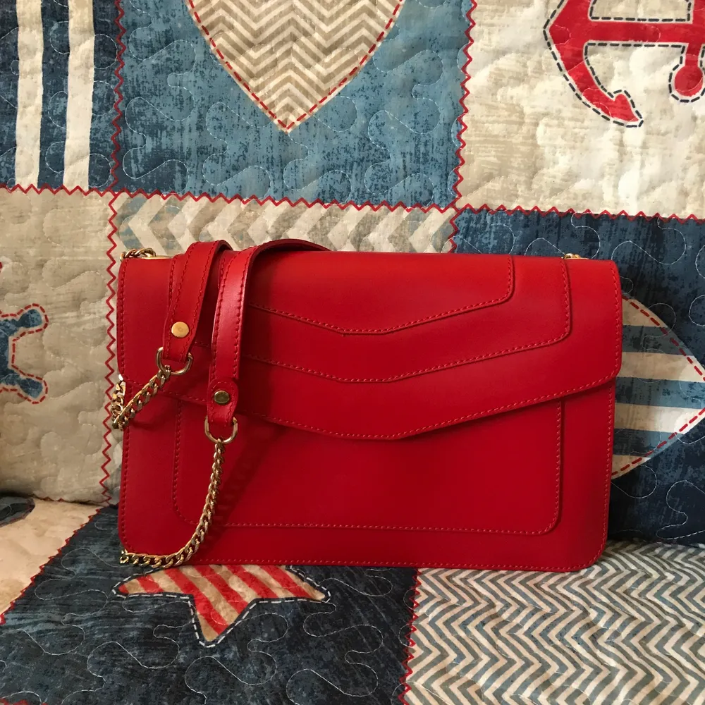 Never worn red leather bag with gold hardware. Bought from Italy. Has a small barely noticeable pen mark on the flap, please see the last photo. This could be easily covered by a pin or scarf. . Väskor.