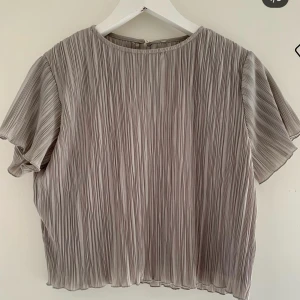 Topp - Super fin ljus grå topp i rynkat material är så skön och super snygg både till vardags och festligare. Är från Nakd X Hanna licious kollektion. Passar både 34 och 36 (Xs/S) 