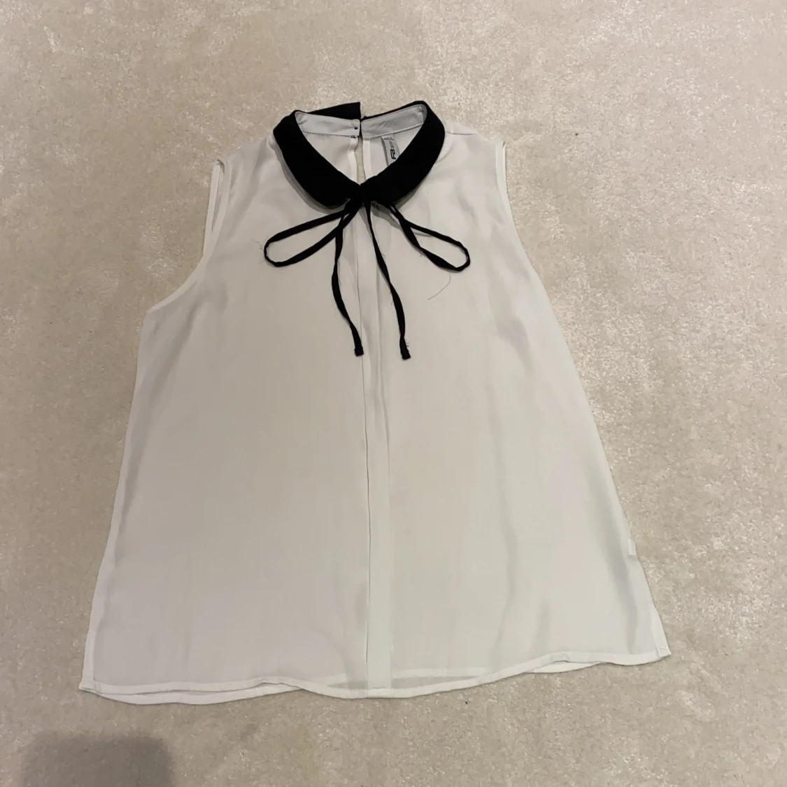 Vit blus med svarta detaljer.