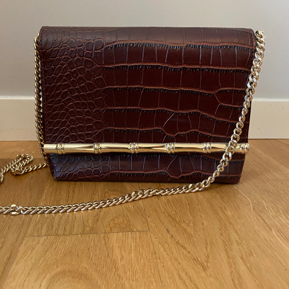 Mörkröd väska med guldig kedja  - 90