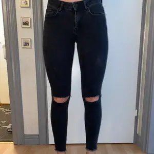 Svarta jeans med slitna knän. Lågmidjade storlek 36. Köparen betalar för frakten 