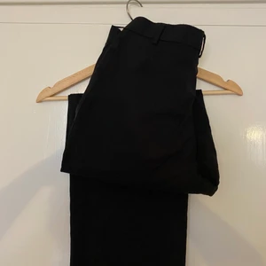 Svarta kostymbyxor - Svarta kostymbyxor i tunt material. Sömmen i en av hällarna samt vid anklarna har gått upp, men det är lätt åtgärdat med några stygn. Köpta secondhand.