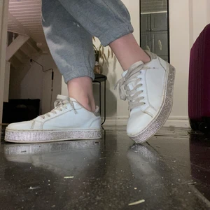 Vita sneakers med glitter - Detta är ett par vita sneakers med glitter på sulan i storlek 34. Skorna är stora i storlek så passar även dem flesta med 35. Dem är lite slitna inuti och dem har tappat några diamanter men det är inget man ser eller tänker på! 