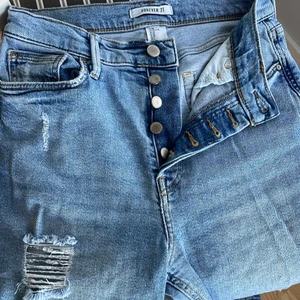Forever 21 jeans - Straight/mom jeans. Högmidjade med knappar. Mycket bra skick. Fickor fram och bak. Strechiga och väldigt sköna att ha på sig. Sitter jättefint 