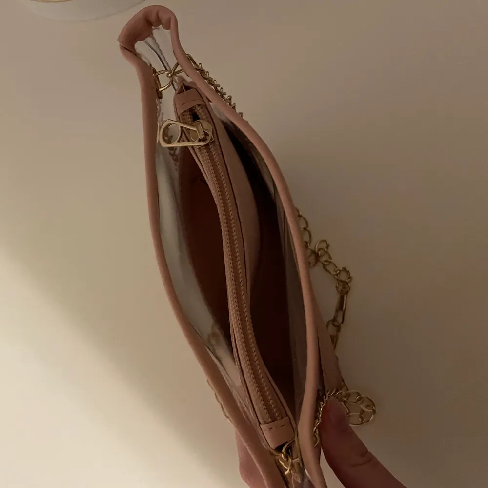 Snygg rosa axelväska med snygga detaljer på utsidan. Guldfärgad kedja. Har en mindre plånbok inuti som man kan lägga mindre saker i!. Accessoarer.