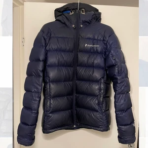 Peak Performance R&D dunjacka mörkblå - Mörkblå dunjacka från peak performance. Varm men samtidigt väldigt lätt, funkar bra för hela vintern. Har huva och bra med fickor. Allmänt bra skick med undantag för en liten defekt vid dragkedjan, fullt fungerande (kan skicka bild). Frakt tillkommer.