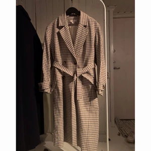 Rutig kappa, H&M - Storlek 38. Mönstret är vitt, svart och beiget/ljusrosa. Passar bäst på en storlek S-L. Kappan är i bra skick förutom en liten fläck på skärpet. Använd sparsamt. Köpt från H&M ca 2018 för ungefär 900.