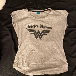 En grå pyjamaströja  - En helt vanlig grå pyjamaströja med wonder woman märke på. Använd några gånger men inte sliten på något sätt. Vet inte vart den är ifrån då jag fick den någon jul