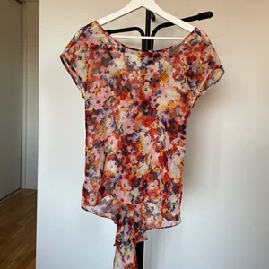 Blommig topp - Supersöt färgglad topp i blommigt mönster! Tyvärr har den blivit för liten för mig 🥺 modellen är lite längre baktill vilket gör den unik. Frakt tillkommer! 