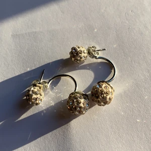 Böjda örhängen - Silvriga och vita böjda örhängen med glas kristaller. Ej använda. (Kommer helt nytvättade) betalning sker över swish (köpare står för frakt)