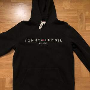 En stilren Tommy Hilfiger hoodie i svart med herrstrl M. Inköpt hösten 2020 på NK i Sthlm för 1200kr. Använd mycket sparsamt och knappt använd, så gott som ny! Pris: 400kr