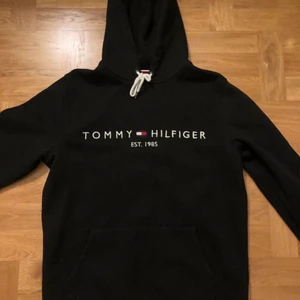 Tommy Hilfiger Hoodie - En stilren Tommy Hilfiger hoodie i svart med herrstrl M. Inköpt hösten 2020 på NK i Sthlm för 1200kr. Använd mycket sparsamt och knappt använd, så gott som ny! Pris: 400kr