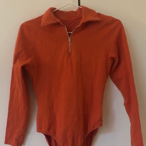 Orange body  - Orange långärmad body med krage och dragkedja, från Humana.  