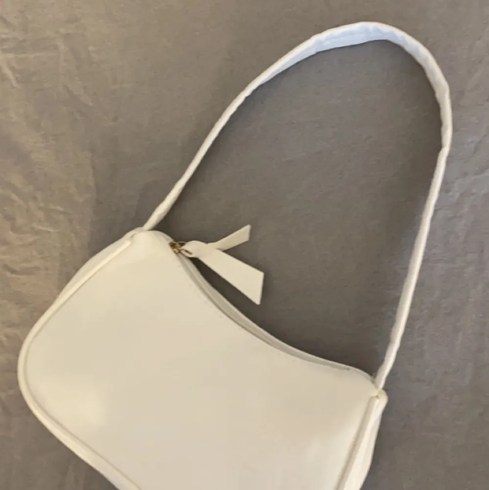 En vit väska i skinn med ett kort axelband och väldigt rymlig , skit snygg men kommer sällan till användning, köparen står för frakten 💖. Väskor.