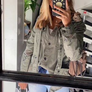 Grön jacka - Knappar och har två stora fickor som går att stänga