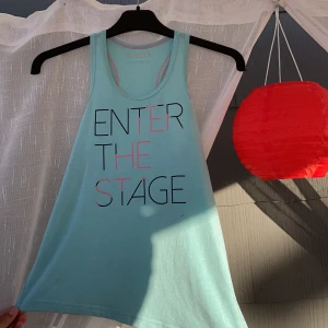 SOC, ljusblå linne - Ett ljusblått linne med en svart rosa text. Öppen flärp på ena sidan, går att knyta den. 