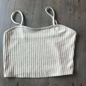 Beige  - Ett beige linne som är rundat högst upp och ribbat. Köparen står för frakten 