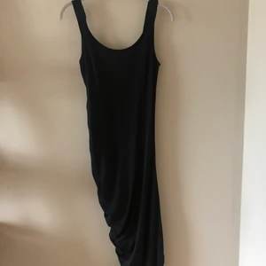 Svart midiklänning - Säljer då den är för tight för mig. Klänningen kanske ser lit konstig ut på bilden, men det är för att den är ”veckad” på en sida så att den ska ha nästan som en slits på ena sidan. Det blir jättesnyggt när man väl har den på sig. 