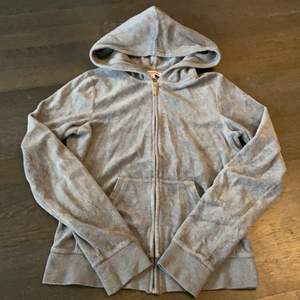 Grå zip hoodie från Juicy Couture med guldtryck på ryggen. Stängs med gullig dragkedja fram. I det klassiska plysch materialet. 