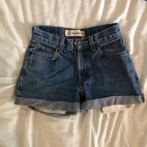 Levi’s jeansshorts - Ett par jeansshorts från Levis i klassisk denimfärg. Nu försmå men när jag använde dom var dom så snygga på. Dragkedja vid gylfen, hög formande midja och fickor fram och bak. Köpare står för frakt. Jag samfraktar!