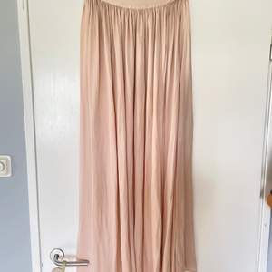 Lång kjol med slits i ljus/gammel rosa. Silkes liknande material.