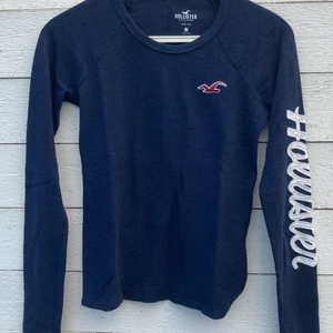 Långärmad tröja, mörkblå - Snygg mörkblå tröja med rött märke och vit text längs ena armen. Från Hollister och bara använd ett par gånger