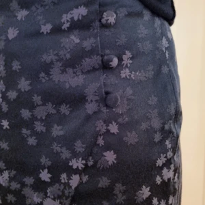 Dagmar kjol - Svart Dagmar kjol i storlek 36. Fina detaljer med grå blommor och fina knappar. Helt oanvänd.