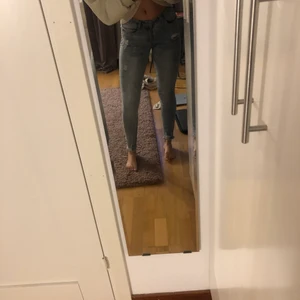 Ljusblå rippade jeans - Slimfit jeans med lite slitningar gärning var. Fickorna och nere vid anklarna är det även slitet. Lågmidjade. Modell: 165 cm