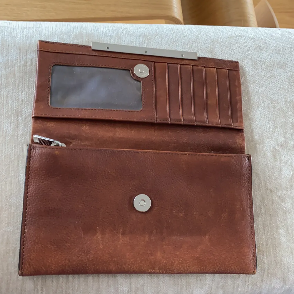 Cognacsbrun plånbok från Tiger of Sweden. En del färgskiftningar i skinnet som ses på bilderna. Sedel-mynt och kortfack. Nypris ca 800kr. . Övrigt.