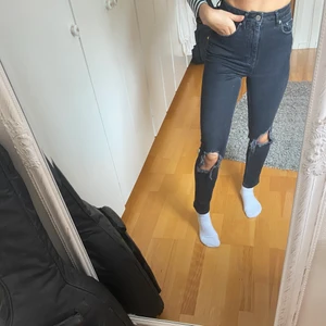 Högmidjade svarta håliga jeans - Ett par högmidjade svart jeans med hål på knäna, i storlek XS från Gina Tricot. Använda ett fåtal gånger. Buda gärna i kommentarerna. Kraaam <3