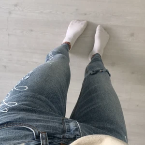 Jeans  - Supernsygga jeans med textdetalj och små slitningar. Även ”hål” på ena knät. ”Avklippta” längst ner vid ankeln. Fin ljusblå färg. Ganska långa. Minns inte vart de är ifrån.