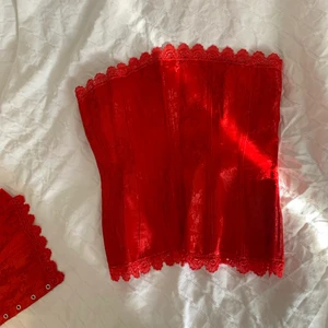 Röd korsett  - Fin korsett med reglerbara spännen. Man kan dra åt den i midjan. På bilden (3) sitter den lite snett!