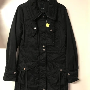 Jacka  - Svart snygg och bekväm lång jacka med mycket fickor. Frakt tillkommer.