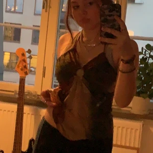 Brun, grön top - Den här toppen har en ring i mitten där fram, luftigt material, man kan knyta där bak o är öppen där bak❤️