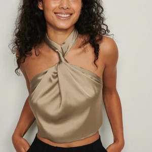 Top med vridning fram - Topp med vridning fram och öppen rygg, använd en gång! Från NA-KD, helt slutsåld. Storlek 34 men passar både större och mindre eftersom man knyter själv i ryggen