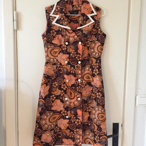 Fransk vintage klänning strl.38 - Vintageklänning från Frankrike. Uppskattar storleken att motsvara en svensk 38, men med skärp i midjan kan den vara fin även på mindre. Jättefint mönster och vitt kantband. Ungefär knälång